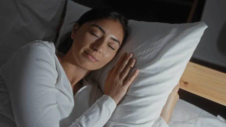 Person sleeping peacefully on white pillow in minimalist bedroom setting